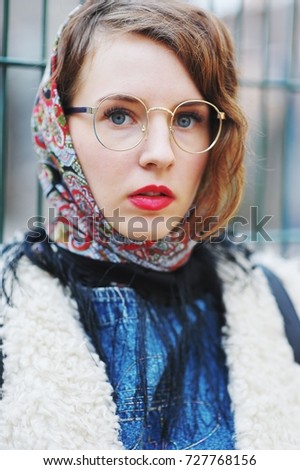 Portrait of young successful beautiful women with perfect makeup wearing a colorful headscarf and a white coat outdoors, closeup