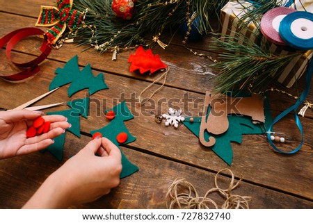Holiday preparation. Christmas and New Year. Unrecognizable woman decorating green felt fir tree on wooden background, festive handmade decoration concept. View from shoulder
