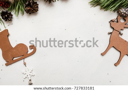 Festive background of winter holidays decoration. Pine branch with strobila and wooden ornaments on white backdrop, top view copy space. Celebration, New Year, Christmas, homemade decor concept