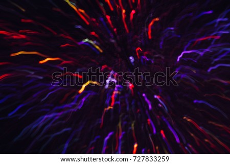 Abstract background of colorful lines in motion on black. Bokeh of defocused curves, blurred red, yellow and violet neon leds, festive backdrop of holidays and celebrations, fireworks and salute