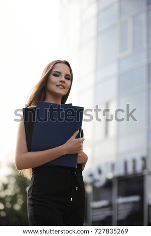 Girl with documents at a business meeting near a modern building
