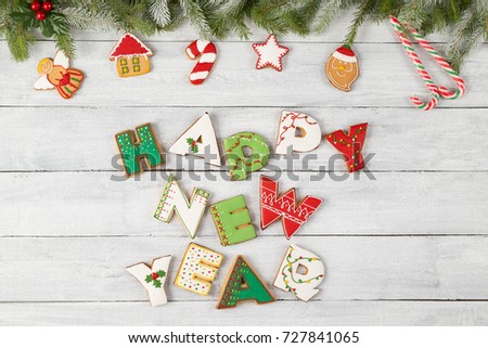 Top view of nicely decorated colorful Christmas cookies shaped like letters Happy New Year on wooden background