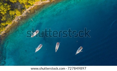 Aerial view of group of sailing boats anchoring next to reef. Bird eye view, water sport theme.