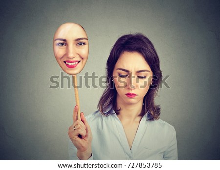 Sad woman looking down taking off happy mask of herself  Royalty-Free Stock Photo #727853785