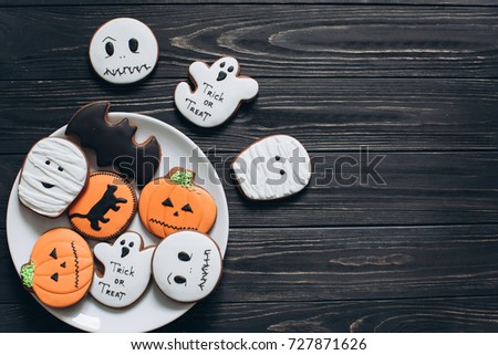 A preparation for Halloween. A plate with scary gingerbreads on a black wooden background.