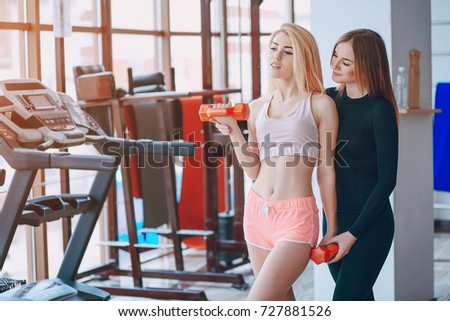 two beautiful girls exercising and stretching at the gym together