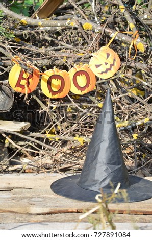 Black witch hat. halloween concept magic witchcraft, inscription BOO wording with Self Made hand drown Smiley face Halloween. orange and yellow on the forest background.