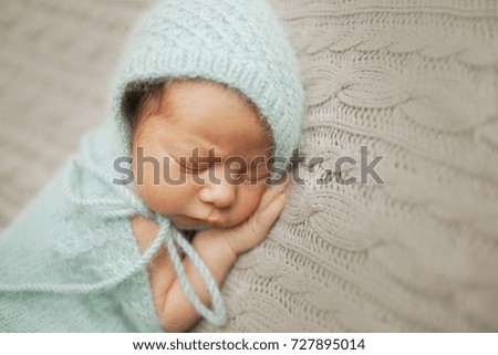 Tiny baby in mint dress sleeps on the woolen blanket