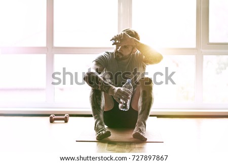 handsome sporty man resting, having break drinking water after doing exercise Royalty-Free Stock Photo #727897867