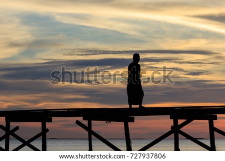 silhouette Muslim man walk on the wooden jetty during sunset at Mantanani Island, Kota Belud, Sabah, Malaysia