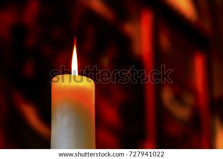 Red flame of a wax candle gives beautiful light and shadows