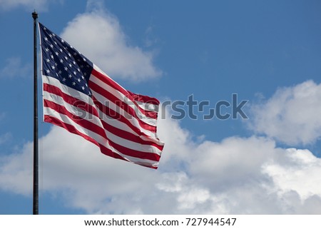 Flag of United States of America (USA) waving in the wind with blue sky and clouds on background