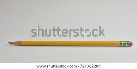 Sharpened yellow pencil with green metal piece holding pink eraser on white background.