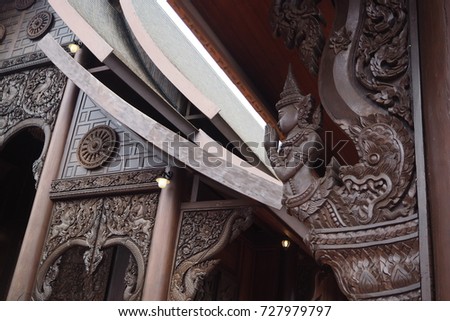 An old delicate design of  teak wooden sculpture at the temple with the picture of male angle raising hands m, serpent as a part of the wall and roof of church