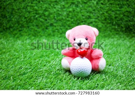 Pink bear with golf ball on green grass