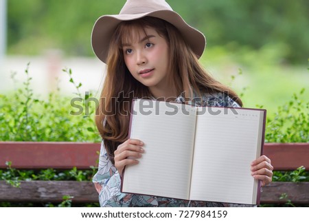 Beautiful asian woman relaxing by reading book in park
