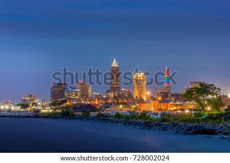 Bright image of the city of Cleveland at dusk with many building lights on.