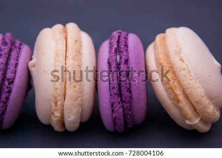 Row of Sweet Purple Violet French Macaroons or Macaron in Row. Many Biscuits on Dark Blue Background