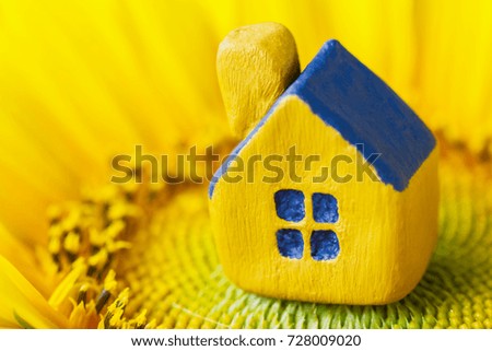 Miniature yellow toy house on the sunflower. Selective focus