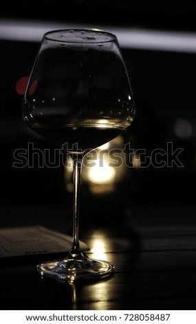 Red wine glass in low light with candle light background, shadow of glass