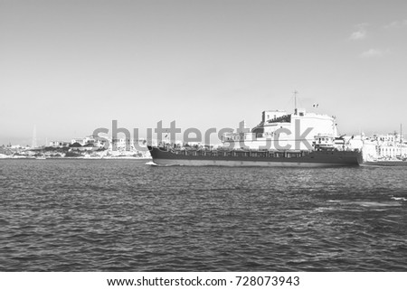 Cargo ship leaves the harbor of Valletta. Black and white picture