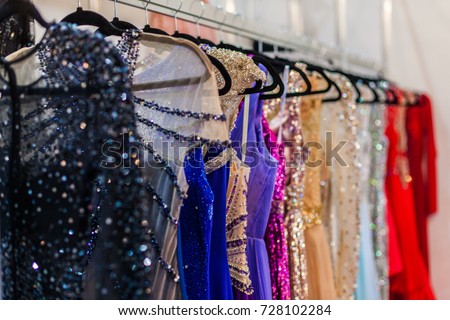 A lot of shiny evening gowns hang in the store Royalty-Free Stock Photo #728102284