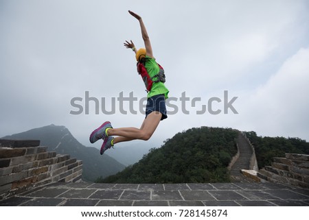 successful woman hiker jumping on great wall