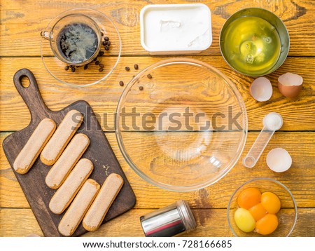 Image on top of cookie on cutting board, eggs, cup, cream cheese, coffee, grains