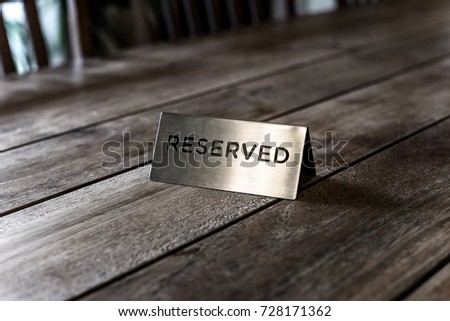 Reserved Metal Plate on the wooden Table. Reservation Seat at restuarant.