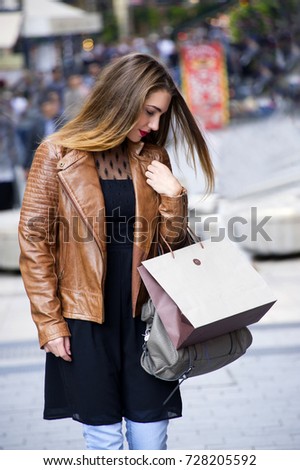 Trendy young woman walking and shopping in city with paper bags in her hand. City style conception.