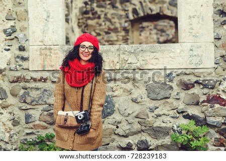 Happy young woman with a vintage camera walking in autumn park.