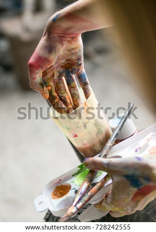 Closeup of paintbrush in woman hands mixing paints on palette