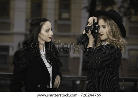 One blond girl photo shooting another brunette girl with old camera