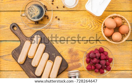 Picture of wooden table with components for tiramisu, raspberry, space for text