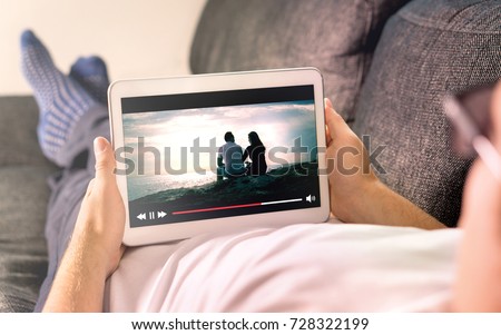 Online movie stream with mobile device. Man watching film on tablet with imaginary video player service.