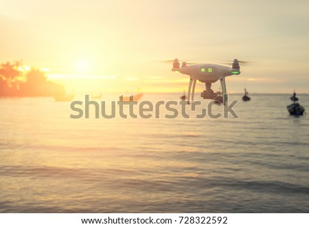 Drone quad copters with high resolution digital camera flying over the sea with sunset orange sky