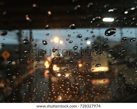 Blurred background, Raindrops on the windshield, street lights at night in rainy day, abstract of colorful bokeh.