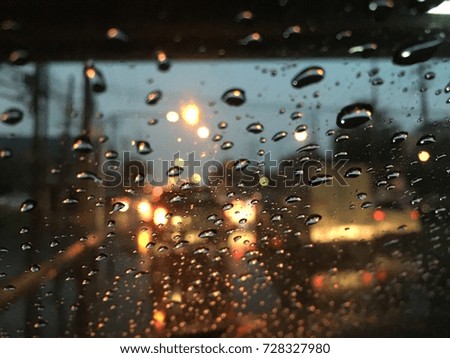 Blurred background, Raindrops on the windshield, street lights at night in rainy day, abstract of colorful bokeh.