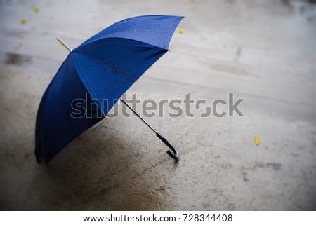 The blue umbrella was placed on the ground on a rainy day. It is a sad day.