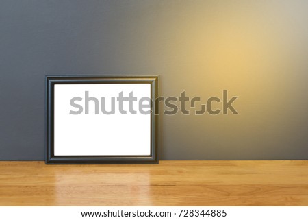 Photo frame on wooden table and cement wall background