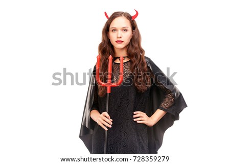 Young woman in Halloween costume posing against white background in studio