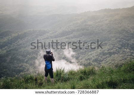 Young man taking pictures view forest floor on top of a high mountain.