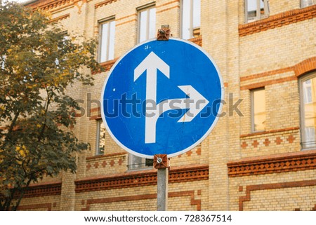 blue traffic sign with white arrows