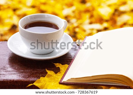 A cup of tea with a book, autumn leaf.