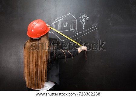 girl secretary in an orange construction helmet measures the size of a drawing