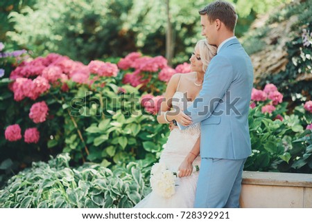 Beautiful wedding couple bride and groom at wedding day outdoors . Happy marriage couple outdoors on nature, background of the blossoming peonies in a garden