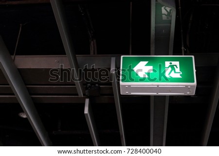 Fire exit sign hanging under ceiling. Selective focus and shallow depth of field.