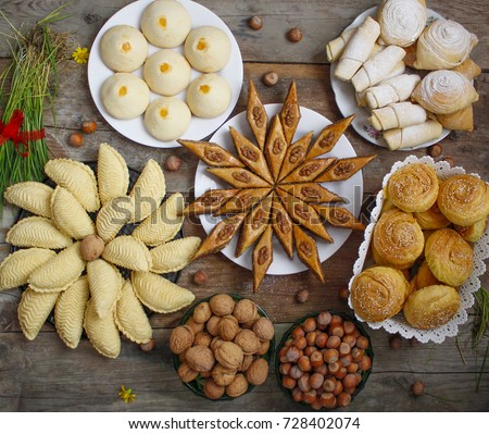 Traditional Azerbaijan holiday Nowruz cookies baklava on white plate on the rustic background with nuts and huzelnuts on green plate and shakarbura,gogal,sweetbread,flat lay