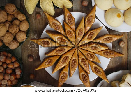 Traditional Azerbaijan holiday Nowruz cookies baklava on white plate on the rustic background with nuts and huzelnuts on green plate ,flat lay