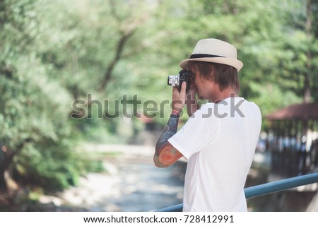 Photographer hipter in hat is taking photos in the park.